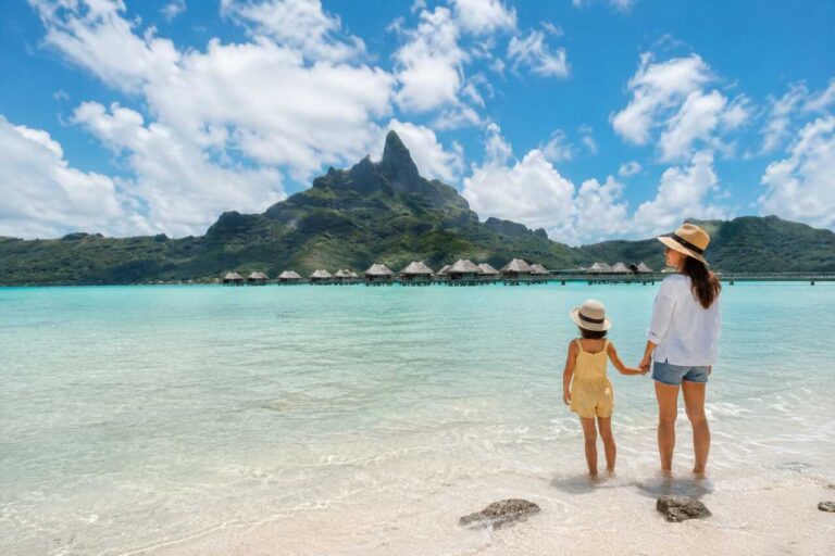 Mother and daughter enjoying a tropical family vacation on a beach with mountain views