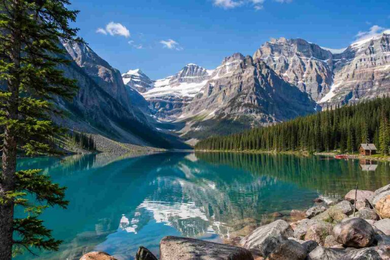 Lake Louise surrounded by turquoise water, evergreen forests, and snow-capped Canadian Rockies in summer