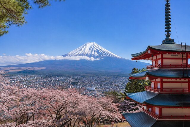 Scenic view of Mount Fuji, a traditional Japanese pagoda, and cherry blossoms overlooking a city.