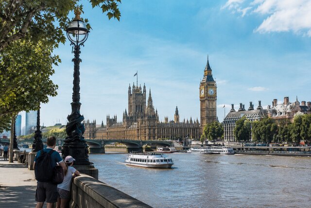 Family viewing Big Ben and the Palace of Westminster along the River Thames in London.
